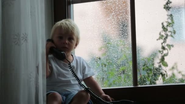 Rozkošný Chlapeček Který Sedí Okenní Štít Mluví Starém Telefonu Deštivého — Stock video