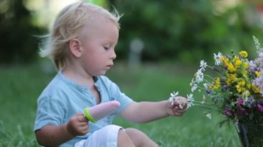 Cute blond toddler boy, eating homemade fruit ice cream