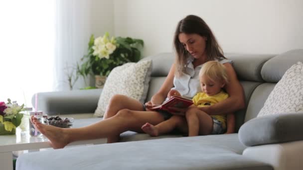 Encantadora Madre Mostrando Imágenes Libro Lindo Bebé Casa Comiendo Cerezas — Vídeos de Stock