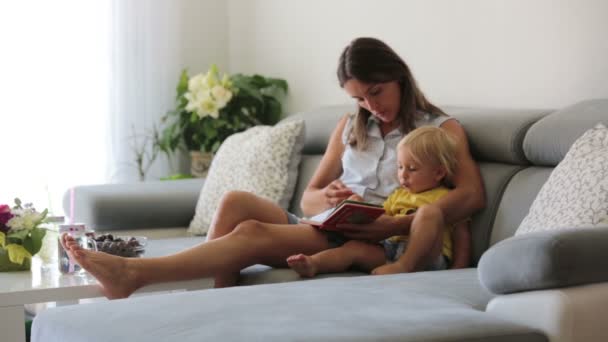 Encantadora Madre Mostrando Imágenes Libro Lindo Bebé Casa Comiendo Cerezas — Vídeo de stock