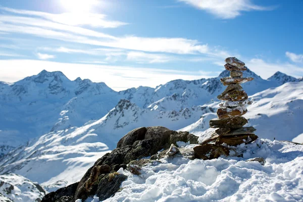 Steinhaufen auf dem Gipfel des Berges bei Sonnenuntergang, Schnee und blauem Himmel — Stockfoto