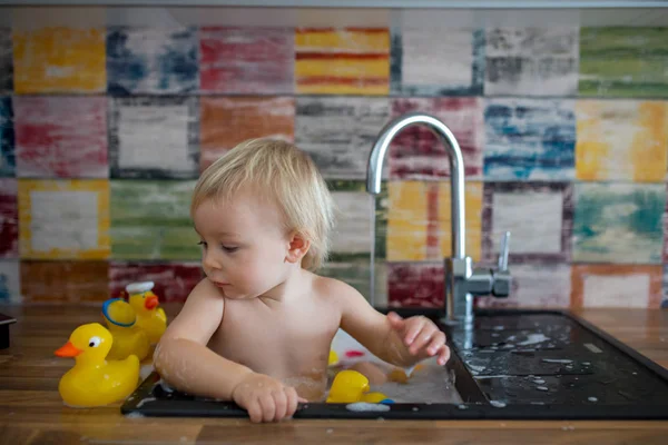 キッチンシンクでお風呂に入るかわいい笑顔の赤ちゃん。子供の遊びのウィット — ストック写真