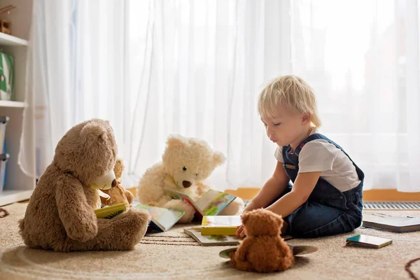 Küçük çocuk, oyuncak ayılarına kitap okuyor. — Stok fotoğraf