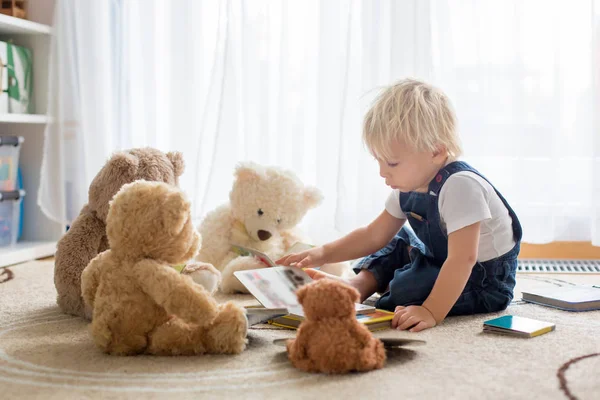 Little toddler boy, reading a book to his teddy bear friends at — Stock Photo, Image