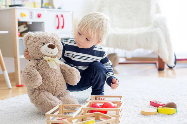 Słodki chłopczyk, bawiący się misiami i drewnianymi zabawkami — Zdjęcie stockowe