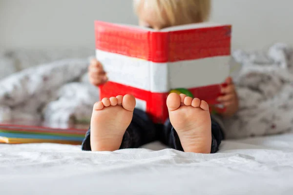 Sladký batole chlapec, čtení knihy doma, sedí v posteli, hodně — Stock fotografie