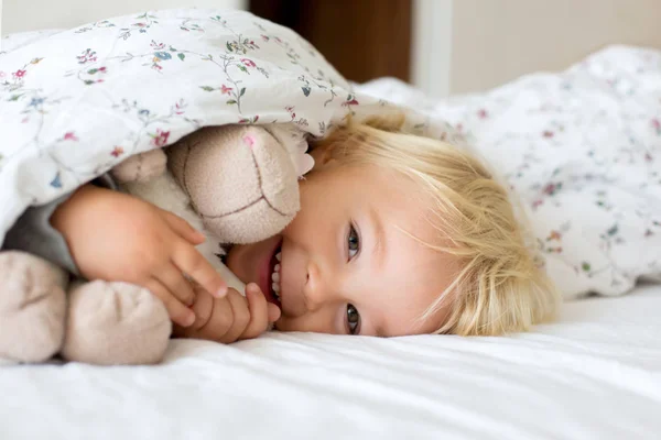 Little toddle boy, playing with teddy toy, hiding under the cove — Stock Photo, Image