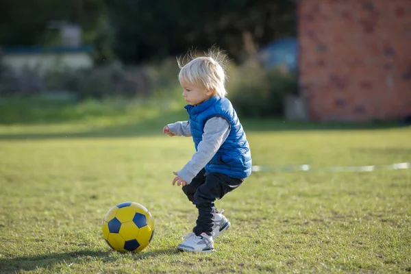 Menino pequeno, jogando com bola de futebol no playground em th — Fotografia de Stock