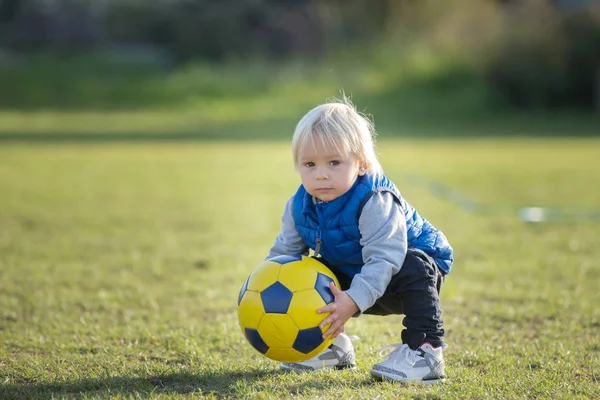 Menino pequeno, jogando com bola de futebol no playground em th — Fotografia de Stock