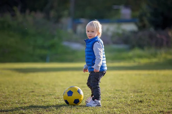 Mały chłopiec maluch, bawi się piłką nożną na placu zabaw w th — Zdjęcie stockowe