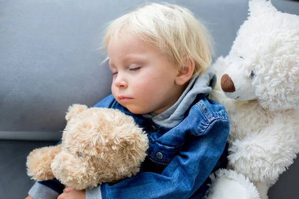 Sarışın çocuk, öğleden sonra bir sürü oyuncak ayıyla yatıyor. — Stok fotoğraf