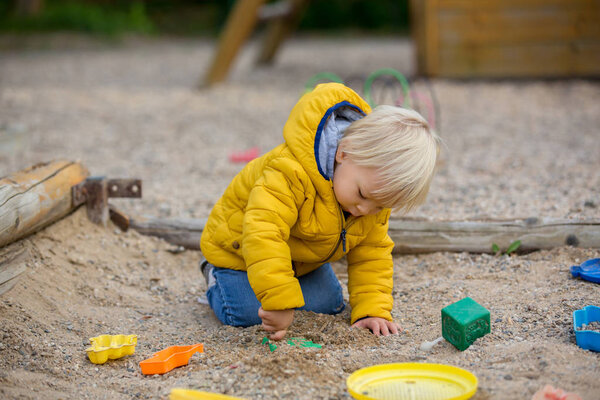 Блондинка ребенок в желтой куртке, играет на pla
