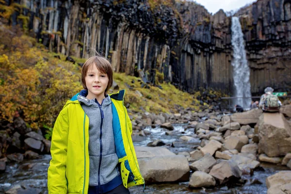 Счастливый ребенок, позирующий перед красивым водопадом Сваровски — стоковое фото