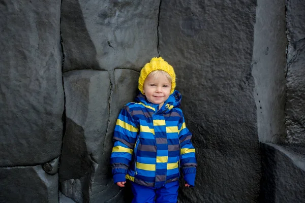 Kleinkind posiert auf dem Felsen des schwarzen Sandstrandes von Reynisfjara — Stockfoto