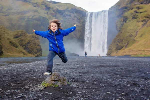 Criança bonita correndo na frente da cachoeira Skogafoss em islandês — Fotografia de Stock