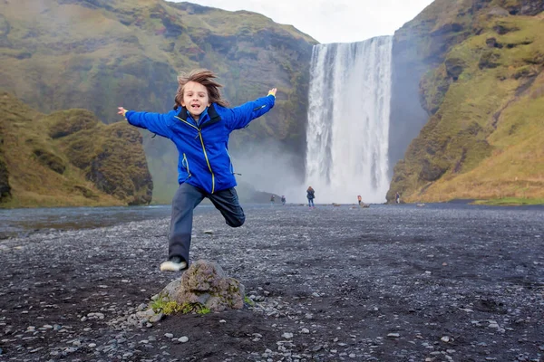 Icelan 'daki Skogafoss şelalesinin önünde koşan tatlı çocuk. — Stok fotoğraf