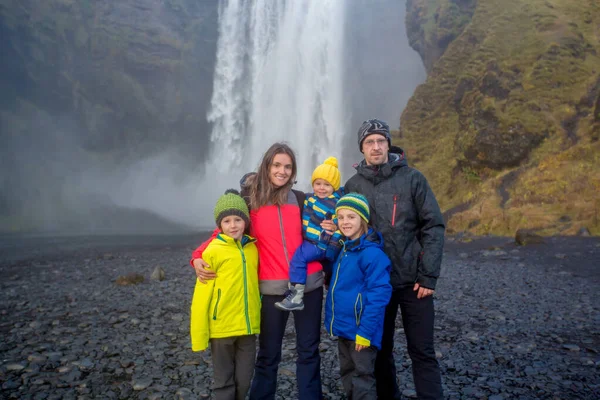 Família feliz, posando na frente da cachoeira Skogafoss em Icel — Fotografia de Stock