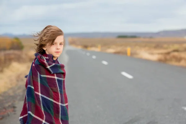 Criança bonita, de pé em uma estrada em um dia muito ventoso, envolto — Fotografia de Stock