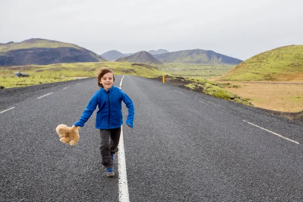Niedliche Vorschulkind mit Teddybär in der Hand, läuft auf einer Straße in — Stockfoto