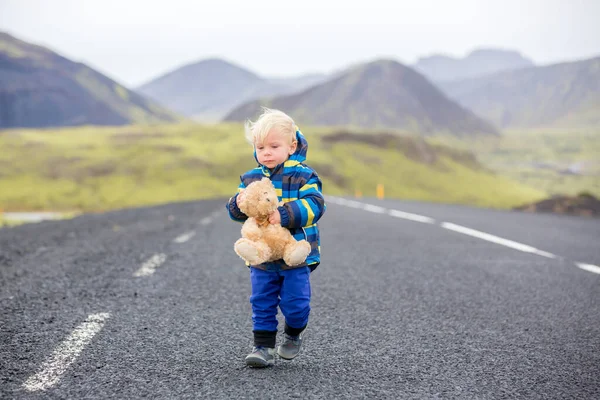 Menino bonito com ursinho na mão, correndo em uma estrada em I — Fotografia de Stock