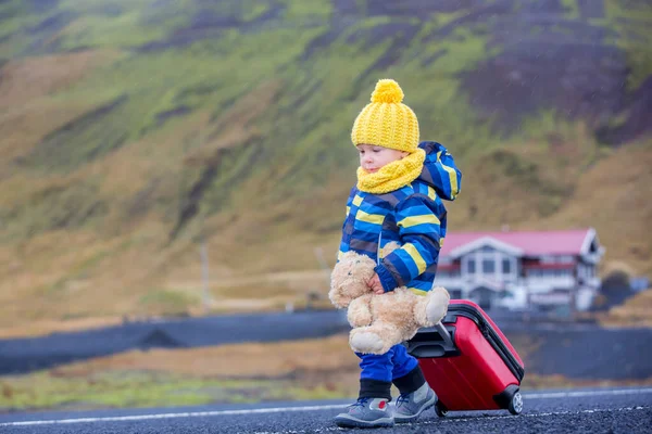 Oyuncak ayısı ve elinde bavuluyla koşan tatlı çocuk. — Stok fotoğraf