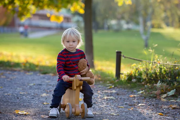 Vacker blond två år gammal småbarn pojke, rider röd trehjuling — Stockfoto