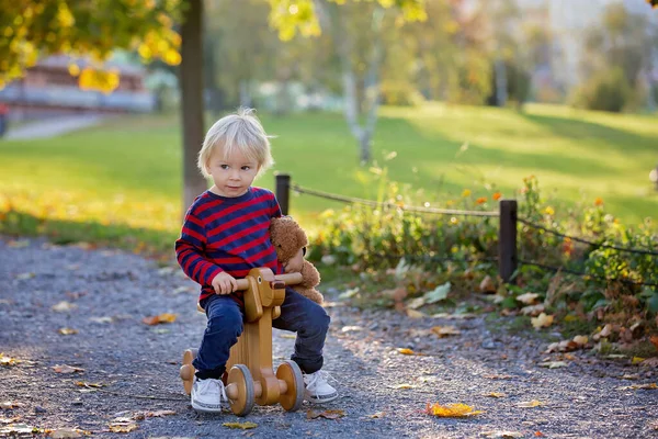 Vacker blond två år gammal småbarn pojke, rider röd trehjuling — Stockfoto