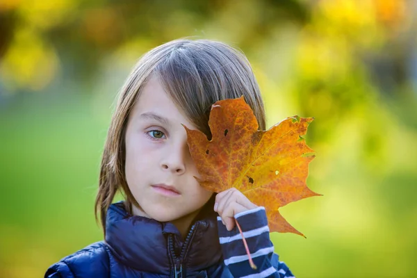 Piękny przedszkolak, trzymający duży liść przed twarzą, — Zdjęcie stockowe