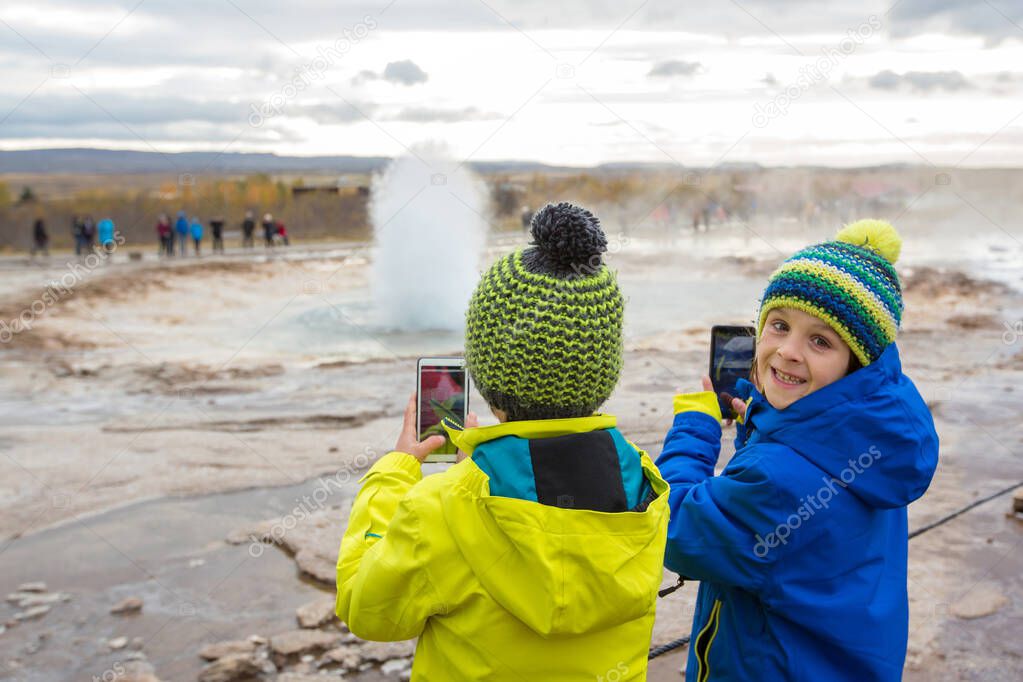 Children, taking picture of Strokkur Geysir while erupting, Icel