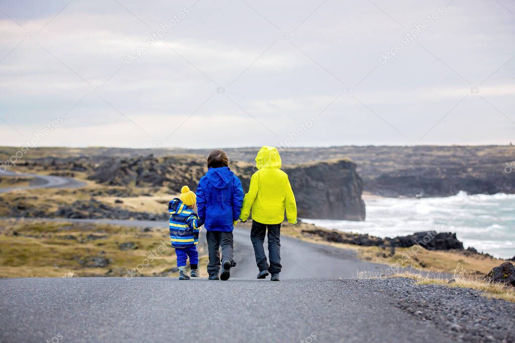 Children, walking on a curved road near ocean in beautiful natur