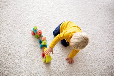 Sevimli çocuk, tahta tren ve oyuncak ayıyla oynuyor.