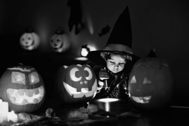 Çocuk, küçük çocuk, evde oyulmuş balkabağıyla oynuyor.