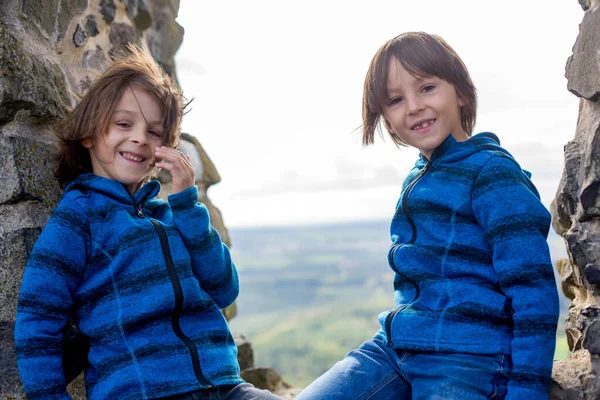 Дети, сидя на каменном окне в старом замке, улыбаясь счастливым — стоковое фото