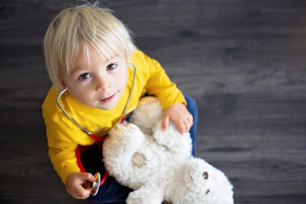 Sött barn, leker doktor, undersöker nallebjörn leksak — Stockfoto