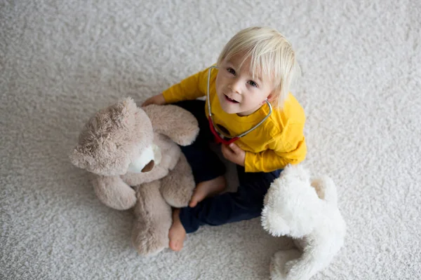 Enfant tout-petit doux, jouant au docteur, examinant le jouet d'ours en peluche — Photo