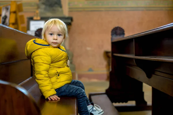 Kleinkind sitzt auf einer Betbank in der Kirche — Stockfoto