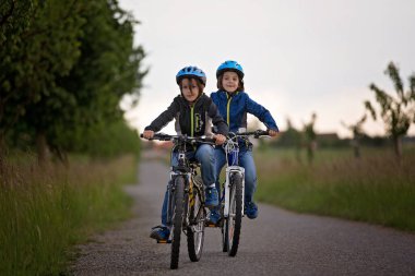 Çocuklar, çocuklar, yağmurlu bir günde birlikte bisiklet sürüyoruz.