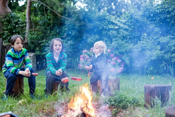 晚上快乐的孩子在篝火上烤香肠 — 图库照片