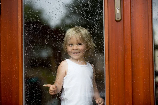 Sad child behind the window on a rainy day