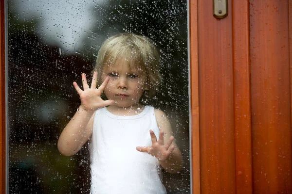 一个可悲的孩子躲在窗后 — 图库照片