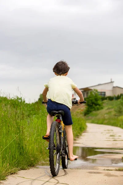 Kind Jongen Rijfiets Modderpoel Zomertijd Een Regenachtige Dag — Stockfoto