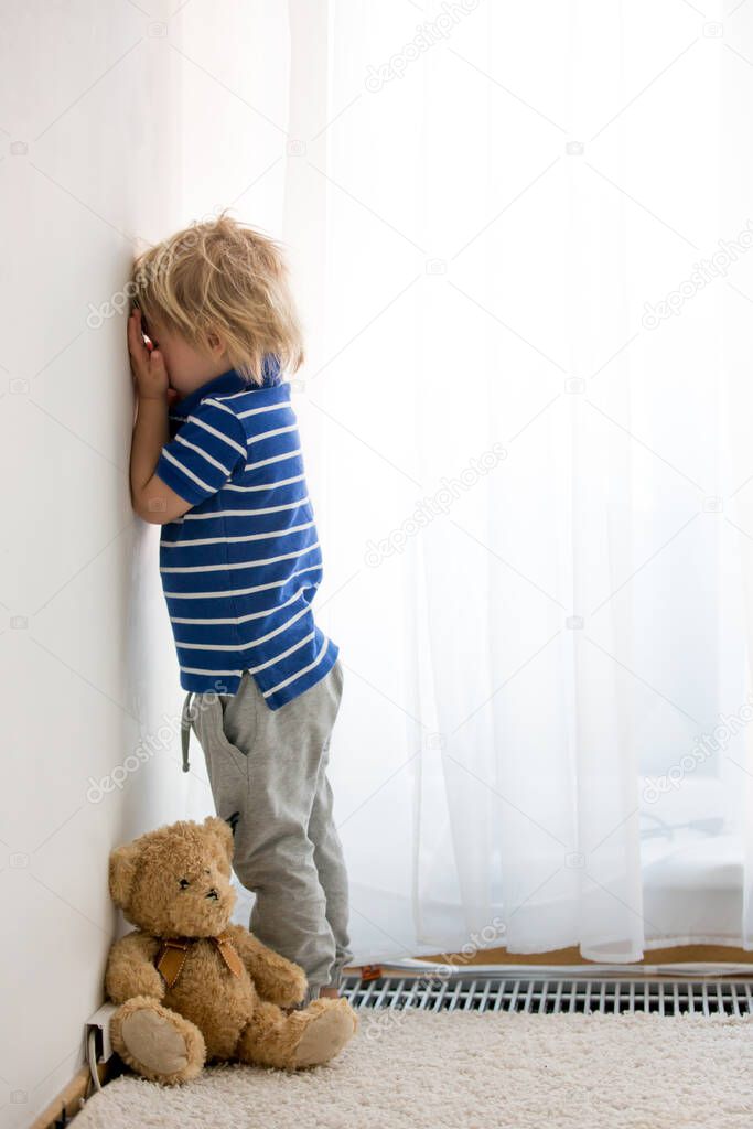 Child, toddler boy, punished in the corner for making mischieves
