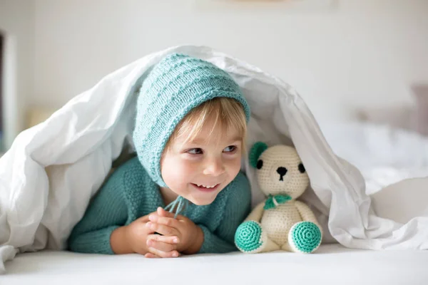 かわいいです幼児の男の子とともに手作りのニットおもちゃ ベッドに横たわっ — ストック写真