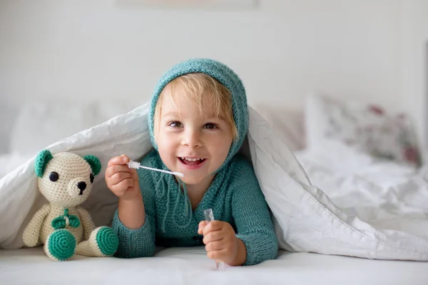 かわいいです幼児の男の子とともに手作りのニットおもちゃ ベッドに横たわっ — ストック写真