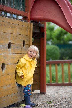 Tatlı çocuk, sarışın çocuk, baharda, bulutlu bir günde oyun parkında oynuyor.