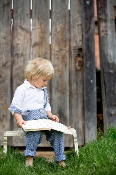 Blond Liten Pojke Läsa Bok Trädgården Framför Gamla Trägrinden — Stockfoto