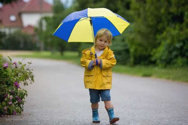 母親と幼児 男の子 雨の中で遊んで ブーツとレインコートを着て — ストック写真