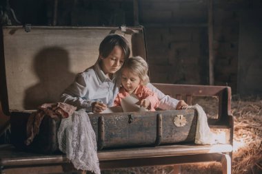 Küçük çocuk, çocuk, tavan arasında eski bir bavulda saklanıyor, bulunamamaktan korkuyor.