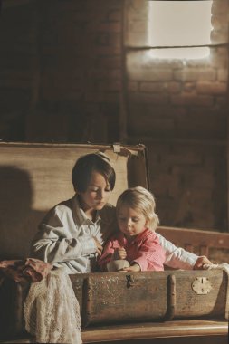 Küçük çocuk, çocuk, tavan arasında eski bir bavulda saklanıyor, bulunamamaktan korkuyor.