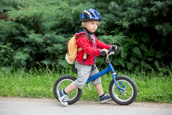 青いヘルメットとかわいい幼児の男の子 路上でバランス自転車に乗る 背景がぼやけて — ストック写真